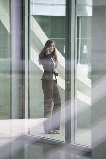 Deutschland, Berlin, Porträt einer Geschäftsfrau, die mit einem Smartphone spricht, lächelnd - FKIF000028