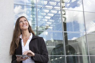 Germany, Berlin, Businesswoman holding digital tablet, smiling - FKIF000031