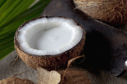 Half coconut with coconut milk and sickle, close up - CSF019616