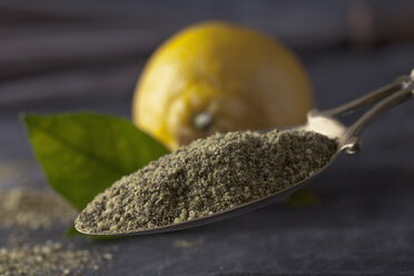 Brass spoon of dried lemon pepper with lemon and leaves on textile - CSF019573