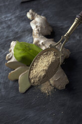 Brass spoon with dried ginger powder on textile, close up - CSF019548