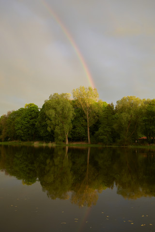 Deutschland, Schleswig Holstein, Blick auf Regenbogen am Kleinen See in der Abenddämmerung, lizenzfreies Stockfoto