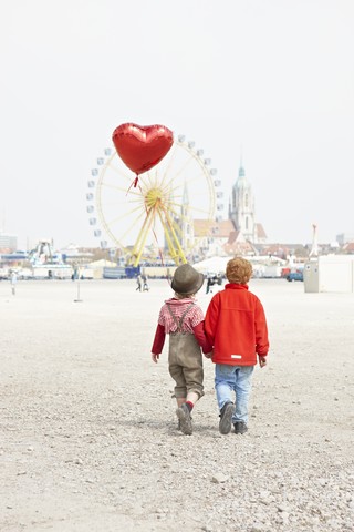 Deutschland, Bayern, München, Jungen mit herzförmigem Ballon auf dem Weg zum Oktoberfest, lizenzfreies Stockfoto