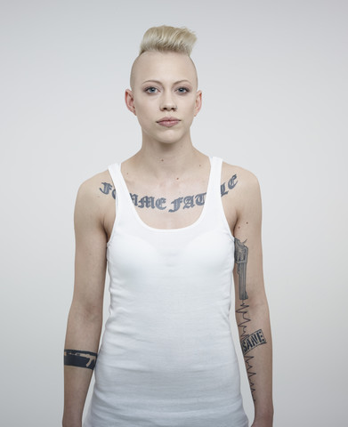 Porträt einer jungen Frau mit Tattoos vor weißem Hintergrund, lizenzfreies Stockfoto