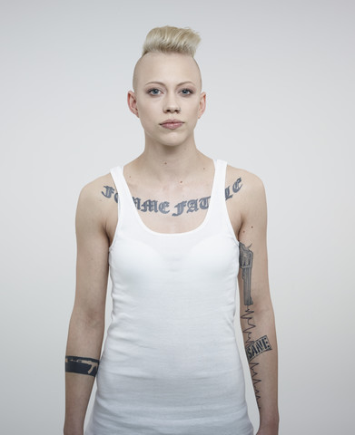 Portrait of young woman with tattoos against white background stock photo