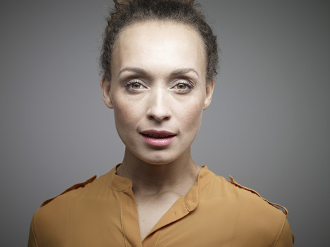 Porträt einer mittleren erwachsenen Frau vor grauem Hintergrund, Nahaufnahme, lizenzfreies Stockfoto