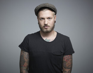 Portrait of young man with tattoos against grey background, close up - RH000219
