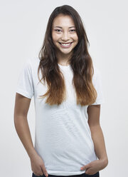 Portrait of young woman against white background, smiling - RH000208