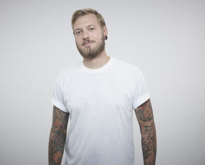 Porträt eines jungen Mannes mit Tattoos vor weißem Hintergrund - RH000207