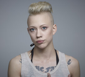 Portrait of young woman with tattoos against grey background, smiling - RH000197