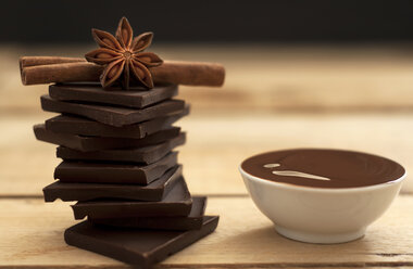 Schale mit Schokoladensauce mit Schokoladenstückchen, Zimt und Sternanis auf Holztisch, Nahaufnahme - OD000027