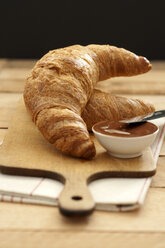 Croissants mit einer Schale Schokoladensauce auf einem Schneidebrett, Nahaufnahme - OD000023