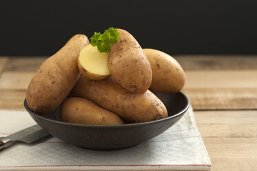 Bowl of potatoes with knife on wooden table, close up - OD000020