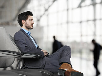 Businessman waiting at airport, looking away - STKF000282