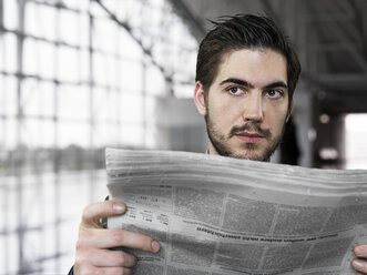 Geschäftsmann, der am Flughafen eine Zeitung hält und wegschaut - STKF000276