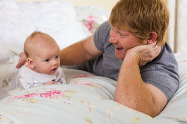 Vater und Sohn auf dem Bett liegend, lächelnd - ABAF000882