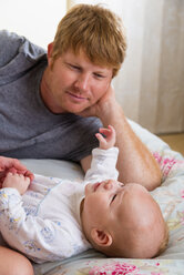 Parents with baby boy on bed - ABAF000942