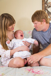 Eltern mit einem kleinen Jungen auf dem Bett, lächelnd - ABAF000943