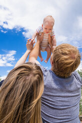 Father holding baby boy up in air against sky - ABAF000929