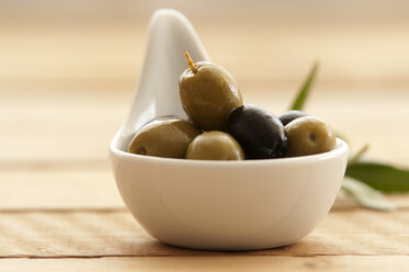 Spoon of olives on wooden table, close up - OD000036