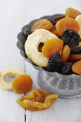 Bowl of dried fruits on wooden table, close up - KSW001082