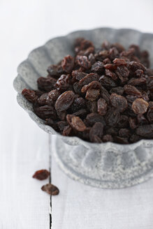 Bowl of raisins on wooden table, close up - KSW001084