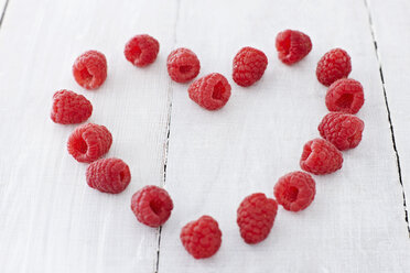 Heart shaped with raspberries on wooden table, close up - KSW001087
