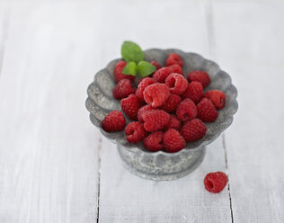 Bowl of raspberries on wooden table, close up - KSW001089