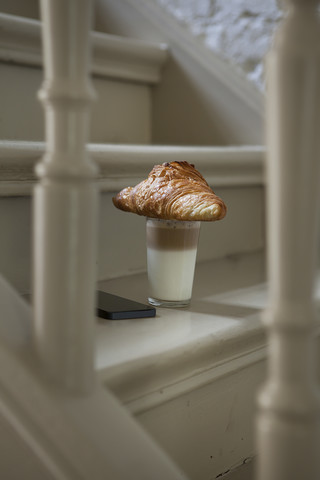 Croissant und Getränk auf der Treppe mit Mobiltelefon, lizenzfreies Stockfoto