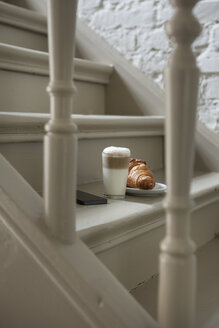 Croissant und Getränk auf der Treppe mit Mobiltelefon - FMKYF000335