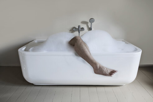 Mittlerer erwachsener Mann in der Badewanne mit ausgestrecktem Bein - FMKYF000283
