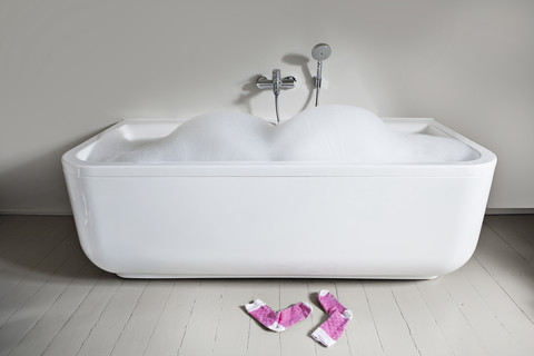 Badewanne mit Seifenschaum und Socken im Badezimmer, lizenzfreies Stockfoto