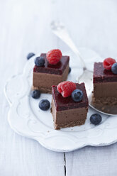 Choco cheesecakes with raspberry and blueberry on plate, close up - KSW001115