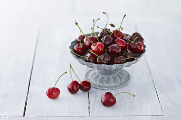 Bowl of cherries on wooden table, close up - KSW001123