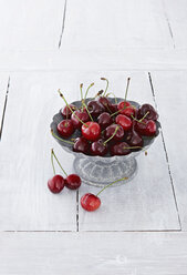 Bowl of cherries on wooden table, close up - KSW001126