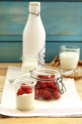 Glass of yoghurt with raspberries on wooden table, close up - OD000066