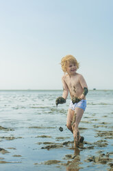 Germany, Schleswig Holstein, Boy playing in mud at beach - MJF000213