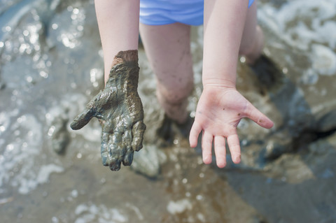 Deutschland, Schleswig Holstein, Junge spielt im Schlamm am Strand, lizenzfreies Stockfoto