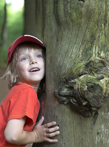 Austria, Boy leaning on tree trunk, smiling stock photo