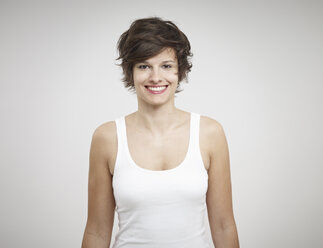 Portrait of young woman standing against white background, smiling - RH000229