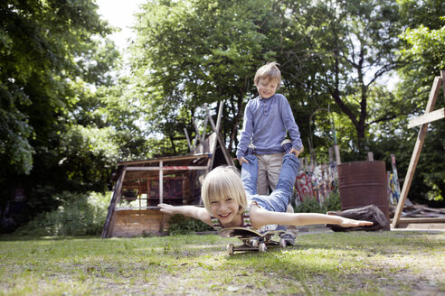 Germany, North Rhine Westphalia, Cologne, Boys playing with skateboard, smiling - FMKYF000432