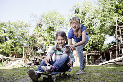 Germany, North Rhine Westphalia, Cologne, Mother and daughter playing with skateboard - FMKYF000397