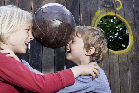 Deutschland, Nordrhein-Westfalen, Köln, Jungen spielen mit Ball auf Spielplatz, lächelnd, lizenzfreies Stockfoto