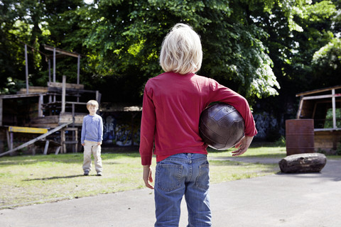 Deutschland, Nordrhein-Westfalen, Köln, Jungen spielen mit Ball auf einem Spielplatz, lizenzfreies Stockfoto
