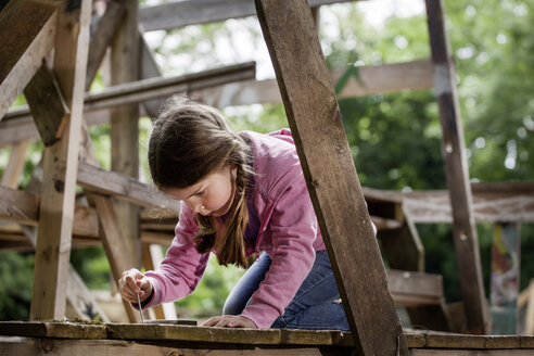 Deutschland, Nordrhein-Westfalen, Köln, Mädchen hält Nagel auf Holz - FMKYF000389