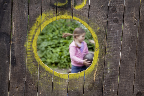 Germany, North Rhine Westphalia, Cologne, Girl playing with ball at playground, smiling stock photo