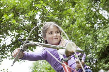 Deutschland, Nordrhein-Westfalen, Köln, Mädchen sitzt auf Fahrrad auf Spielplatz, lächelnd - FMKYF000372