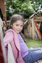 Germany, North Rhine Westphalia, Cologne, Girl sitting on bench at playground, smiling - FMKYF000374