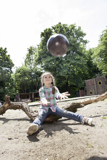 Germany, North Rhine Westphalia, Cologne, Girl playing with ball in playground - FMKYF000401