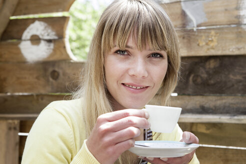 Germany, North Rhine Westphalia, Cologne, Portrait of young woman holding cup, smiling - FMKYF000351